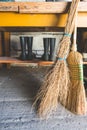 Broom and besom against a wooden table and two rubber boots in a shed