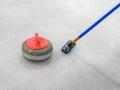 Broom and stone for curling on ice of a indoors rink. Royalty Free Stock Photo