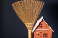 Broom and toy model of a village house on a dark background. Space for lettering and design