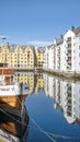 Morning scene with the famous art nouveau buildings reflecting in the pristine waters of Brosundet canal, Alesund, Norway