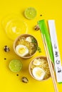 Broth or bouillon with noodle and egg served with thyme and lime in craft containers on yellow background. Soup to go, healthy