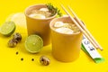 Broth or bouillon with noodle and egg served with thyme and lime in craft containers on yellow background. Soup to go, healthy