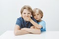 Brother asking to keep secret. Portrait of unhappy annoyed boy sitting at table with hands crossed, frowning while Royalty Free Stock Photo