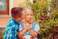Brother boy are kissing his sister girl on the cheek, warm hugs in nature outside near the house. she smiles happy Royalty Free Stock Photo