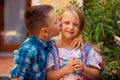 Brother boy are kissing his sister girl on the cheek, warm hugs in nature outside near the house, she smiles happy. Brother and Royalty Free Stock Photo