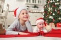 brother with little sister baby in santa hats lie and smile on the background of the christmas tree.