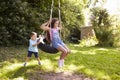 Brother Pushing Sister On Tire Swing In Garden Royalty Free Stock Photo
