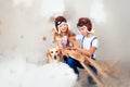 Brother and sister in aviator helmet playing with big wooden airplane in white clouds. Children and their dog together in sky with