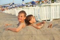 Brother and sister buried in sand on beach