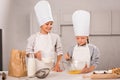 brother and sister in chef hats and aprons whisking eggs in bowl at table Royalty Free Stock Photo