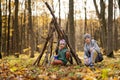Brother with sister constructs a house from sticks in autumn forest