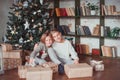 Brother and sister in a cozy room next to the Christmas tree holding gifts. New year concept