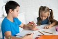 brother and sister doing homework together at table