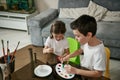 Brother and sister dressed alike coloring Easter eggs with paints Royalty Free Stock Photo