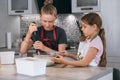 Brother and sister dressed aprons making a homemade pancakes on the home kitchen. Boy using electric mixer for liquid dough mixing