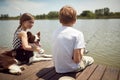 Brother and sister enjoying fishing on the dock with their dog Royalty Free Stock Photo