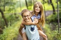 Brother and sister giving piggyback in forest