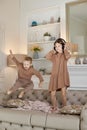 Brother and sister have fun at home and jump on the couch. Children dance and listen to music with headphones.