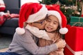 Brother and sister kissing and hugging each other sitting on floor by christmas gifts at home