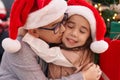 Brother and sister kissing and hugging each other sitting on floor by christmas gifts at home