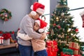 Brother and sister kissing and hugging each other standing by christmas gifts at home