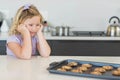 Child resting elbows on white countertop gazing at chocolate chip cookies on baking tray Royalty Free Stock Photo