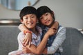 Brother and sister love. Portrait of a cheerful brother and sister holding each other while being seated on a couch at Royalty Free Stock Photo