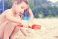 Little cute boy with plastic spatula in hand makes sand castle at the beach. Royalty Free Stock Photo