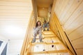 Brother with sister in pajama sit on stairs in cozy wooden tiny cabin house. Life in countryside Royalty Free Stock Photo