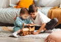 Brother and sister play with wooden toys in children`s room. Children play with a toy designer on the floor Royalty Free Stock Photo