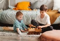 Brother and sister play with wooden toys in children`s room. Children play with a toy designer on the floor Royalty Free Stock Photo