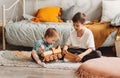 Brother and sister play with wooden toys in children`s room. Children play with a toy designer on the floor Royalty Free Stock Photo