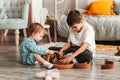 Brother and sister play with wooden toys in children`s room. Children play with a toy designer on the floor Royalty Free Stock Photo