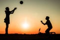 Brother and sister are playing with ball in nature, bicycle lies nearby