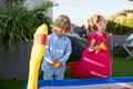 Brother and sister playing fishing in the kiddie pool. Royalty Free Stock Photo