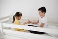 Brother and sister playing a game of rock, scissors, paper on bed at home