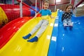 Brother with sister playing at indoor play center playground. Children slides in colored slide Royalty Free Stock Photo