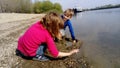 Brother and sister are playing by the river. A boy and a girl are wearing jeans and long-sleeved clothing. Early summer. Smiles