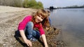 Brother and sister are playing by the river. A boy and a girl are wearing jeans and long-sleeved clothing. Early summer. Smiles