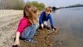 Brother and sister are playing by the river. A boy and a girl are wearing jeans and long-sleeved clothing. Early summer. Smiles