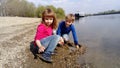 Brother and sister are playing by the river. A boy and a girl are wearing jeans and long-sleeved clothing. Early summer. Smiles