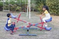 Brother and Sister playing seesaw in the playground.