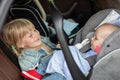 Brother and sister sitting in car in safety seat. Siblings on passenger places having fun together during travel by Royalty Free Stock Photo