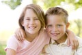 Brother and sister sitting outdoors smiling Royalty Free Stock Photo