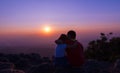 brother and sister sitting on rock and see sunset together at sunset view point background at Phu Hin Rong Kla National Park