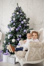 Brother and sister are sitting on a vintage armchair in a white room beautiful decorated for christmas holiday with a Christmas Royalty Free Stock Photo
