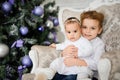 Brother and sister are sitting on a vintage armchair in a white room beautiful decorated for christmas holiday with a Christmas Royalty Free Stock Photo