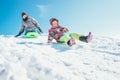 Brother and sister slide down from the snow slope. Winter time p