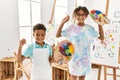 Brother and sister smiling confident holding paintbrush and palette at art studio