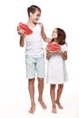 Brother and sister in the studio walk through the white background, eat pieces of watermelon and laugh